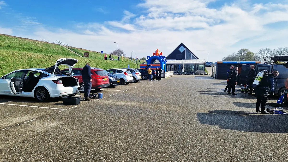 Duikers en auto's op de parkeerplaats bij duikstek Kerkweg in Den Osse
