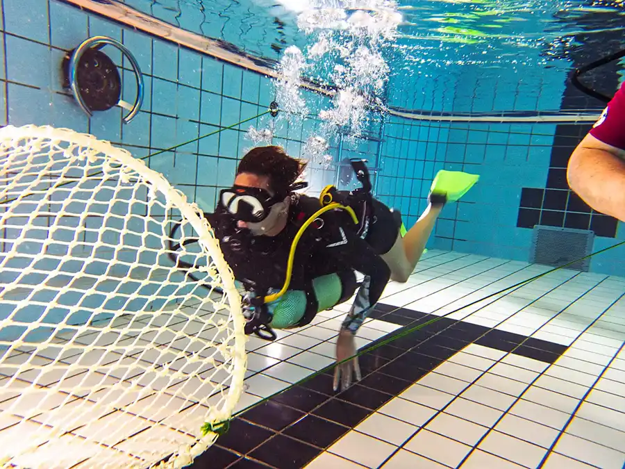 Nettentraining - een duiker houdt de duikset onder zich in plaats van op de rug, voordat ze een nauwe fuik in zwemt